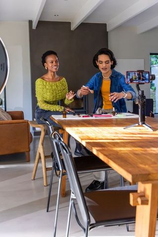 Diverse women filming diy craft tutorial with smartphone and ring light at wooden table