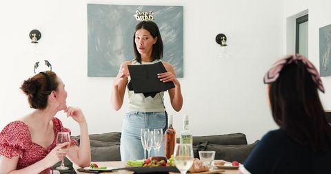 Female graduates celebrating graduation in dining room