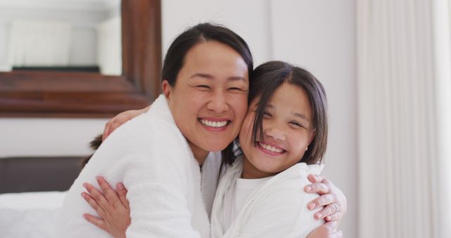 Mother and daughter embracing and sharing a joyful moment. Great for family-themed content, promoting love and connection between parents and children, and showcasing happy family interactions in indoor settings.