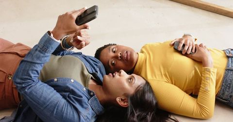 Two diverse women on floor browsing smartphones