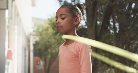 Young Girl with Hula Hoop Outdoors by School Yard