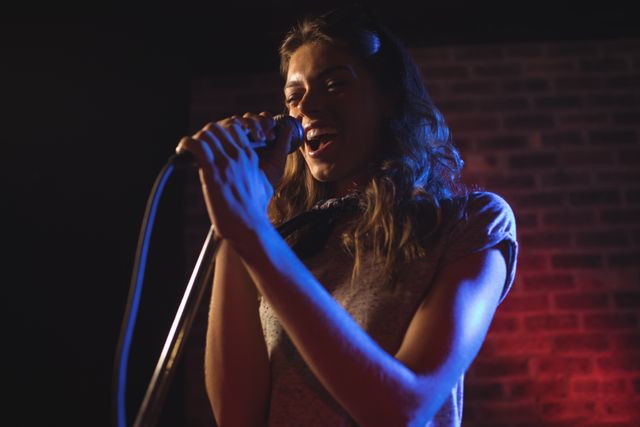 Female singer passionately performing on stage during a music concert. Ideal for use in articles about live music, concert events, music industry, and entertainment promotions.