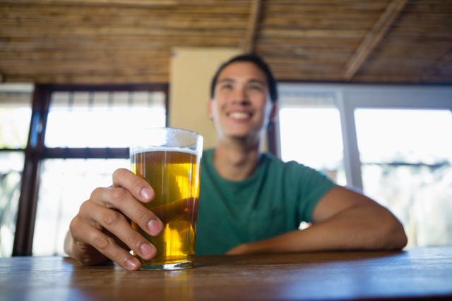 Happy man with beer glass looking away at bar counter