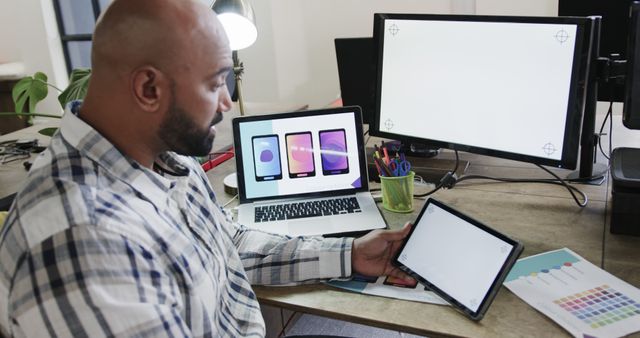 Biracial casual businessman using a laptop, tablet, and computer with copy space in the office - Download Free Stock Photos Pikwizard.com