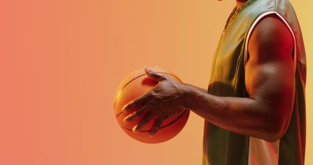 Athletic man holding a basketball against a gradient background, emphasizing his muscular arm and strength. Perfect for materials related to sports, fitness, athletics, training programs, sports equipment promotions, and motivational themes.