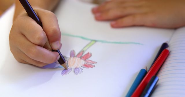 Child coloring flower drawing with colored pencils, highlighting creativity and learning. Ideal for use in educational blogs, websites focused on children's activities, art, creative processes, and early childhood learning.
