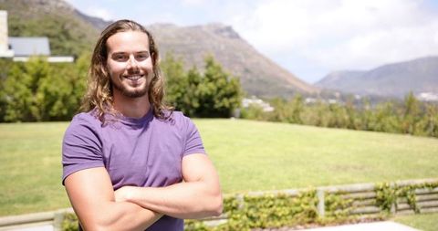 Confident young man in purple t-shirt with scenic mountain background