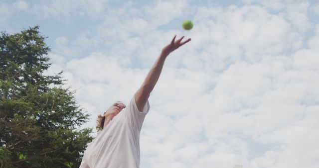 Caucasian male tennis player throwing ball in the air before serving on outdoor court, unaltered. Sport, competition, match, game, hobbies and leisure activities.