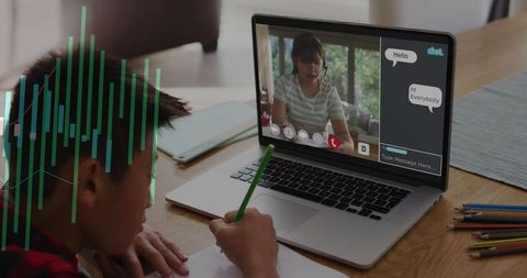 Boy studying remotely with teacher on laptop, writing homework, virtual tutoring