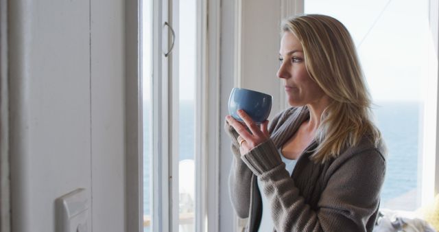Woman Relaxing with Morning Coffee by Window Overlooking Ocean - Download Free Stock Images Pikwizard.com