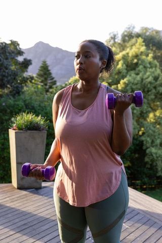 Woman exercising outdoors with dumbbells against scenic mountain backdrop