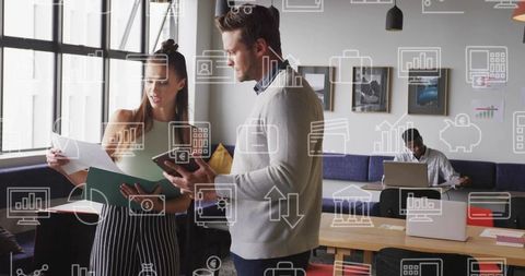 Young professionals reviewing documents in modern coworking lounge with digital icons