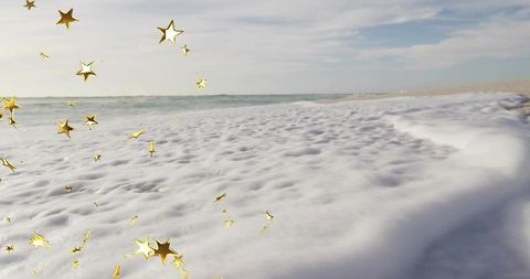 Golden Star Ornaments Above Frothy Sea Foam on Sandy Beach