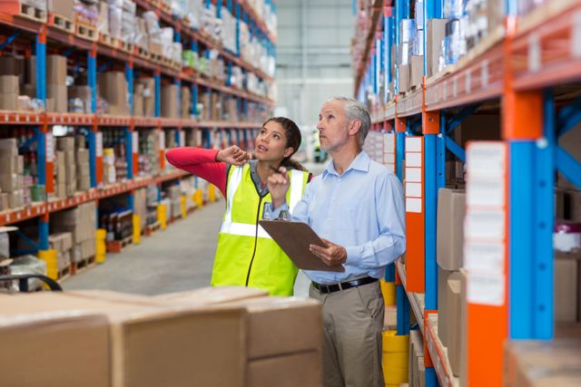 Warehouse manager and female worker interacting while checking inventory in warehouse