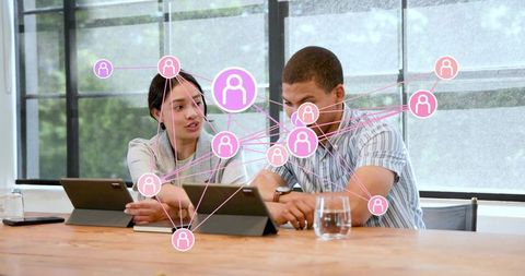 Business colleagues collaborating on tablets with pink network overlay in coworking office