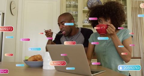 Couple enjoying breakfast with laptop notifications in kitchen