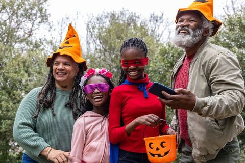 African american family celebrating halloween outdoors wearing pumpkin hats and costumes