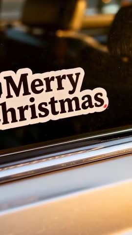 Vertical video centering Merry Christmas sticker on car window at golden hour with chrome trim