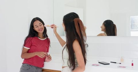 Female Friends Enjoying Makeup Routine in Bright Bathroom