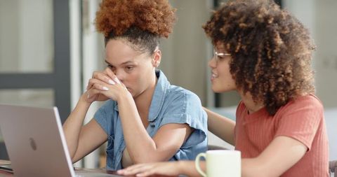 Colleague comforting distressed coworker at laptop desk showing empathy and emotional support