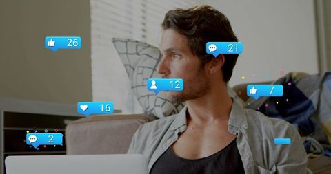 Man checking social media notifications on laptop while relaxing on sunlit sofa
