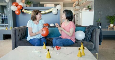 Senior women blowing up balloons for birthday celebration