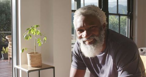 Smiling senior african american man relaxing at home near sunlit windows