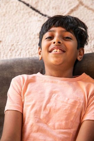 Smiling Preteen Boy Relaxing on Sofa at Home
