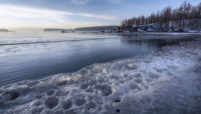 Serene frozen shoreline with calm winter bay reflection