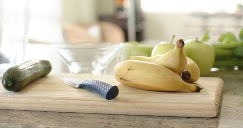 Morning fruit prep with bananas and blue-handled knife on wooden cutting board