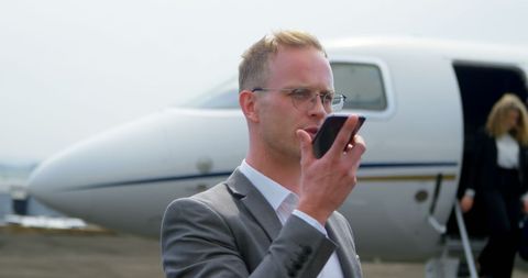 Businessman Communicating on Phone Near Private Jet at Airport - Download Free Stock Images Pikwizard.com