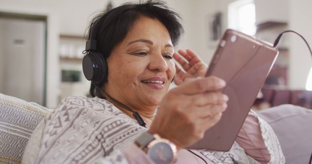 African american senior woman wearing headphones listening to music on digital tablet at home - Download Free Stock Photos Pikwizard.com