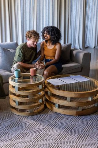 Couple sharing comfort on cozy light gray sofa with wooden coffee tables and mugs