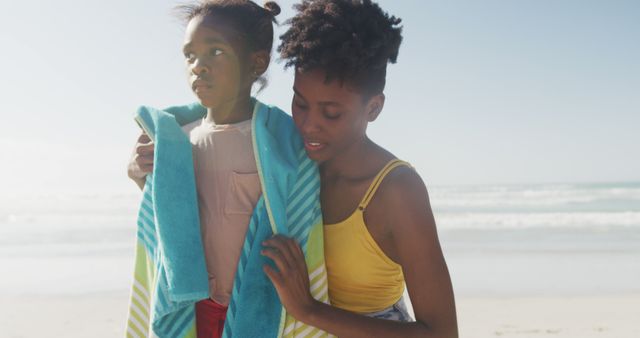 African american mother drying her daughter with a towel at the beach. family travel and vacation concept