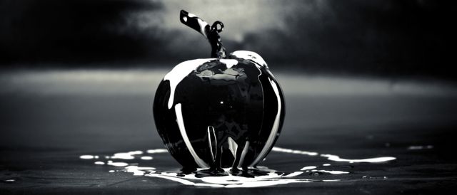 This image demonstrates a creative concept with a glossy apple covered in liquid against a dark background, perfect for marketing materials related to food design, abstract artwork, and creative advertising.