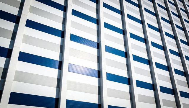 Modern geometric facade with blue and gray striped cladding and vertical ribs