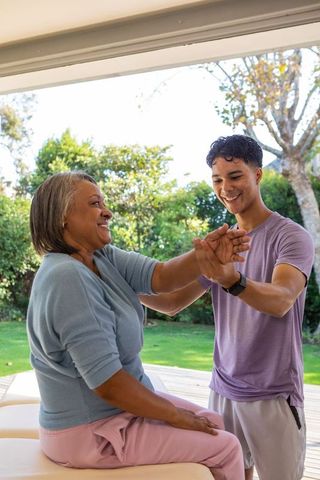 Senior woman enjoying rehabilitative stretch with therapist outdoors