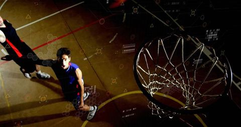 Basketball players attempting slam dunk on indoor court