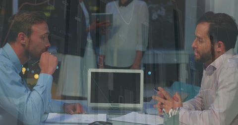 Businessmen analyzing data and shaking hands in office
