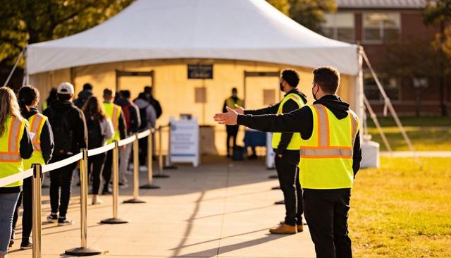 Campus volunteers directing outdoor queue to white tent for testing and registration