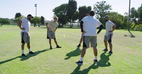 Men warming up in semicircle on grass field during outdoor team training session