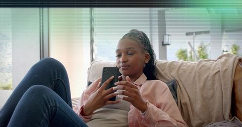 Relaxed woman lounging on sofa using smartphone, casual home lifestyle moment