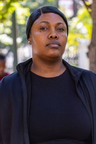 Confident african american woman wearing black zip-up jacket urban park portrait in daylight