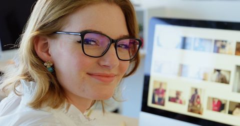 Smiling female graphic designer with glasses in office