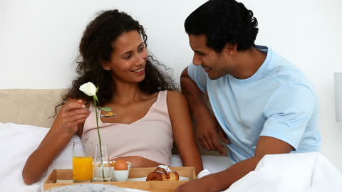 Happy Couple Enjoying Breakfast in Bed Smiling Together