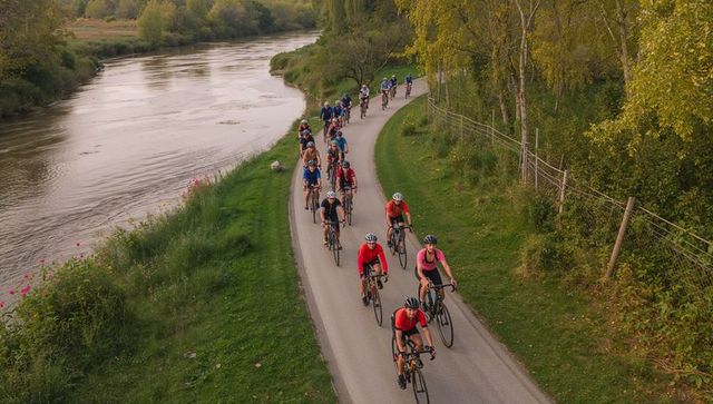 Cyclists Riding Along a Serene Riverside Trail at Sunset