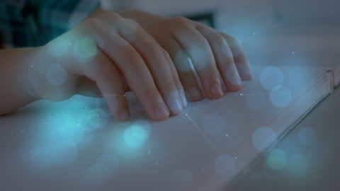 Close-Up of Hands Reading a Braille Book with Blue Light Effects