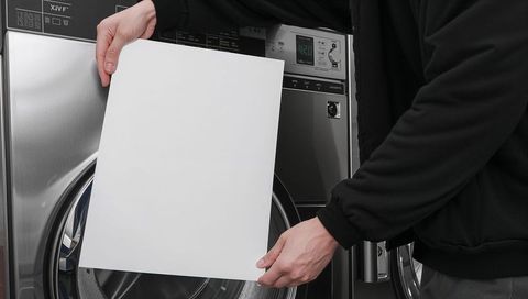 Person holding blank paper hiding washing machine door panel