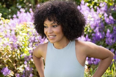 Smiling African American Woman Enjoying Garden with Vibrant Purple Blooms