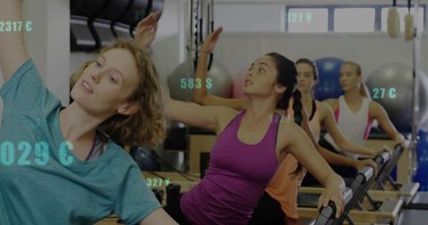 Women practicing reformer pilates balancing on reformers in group fitness class